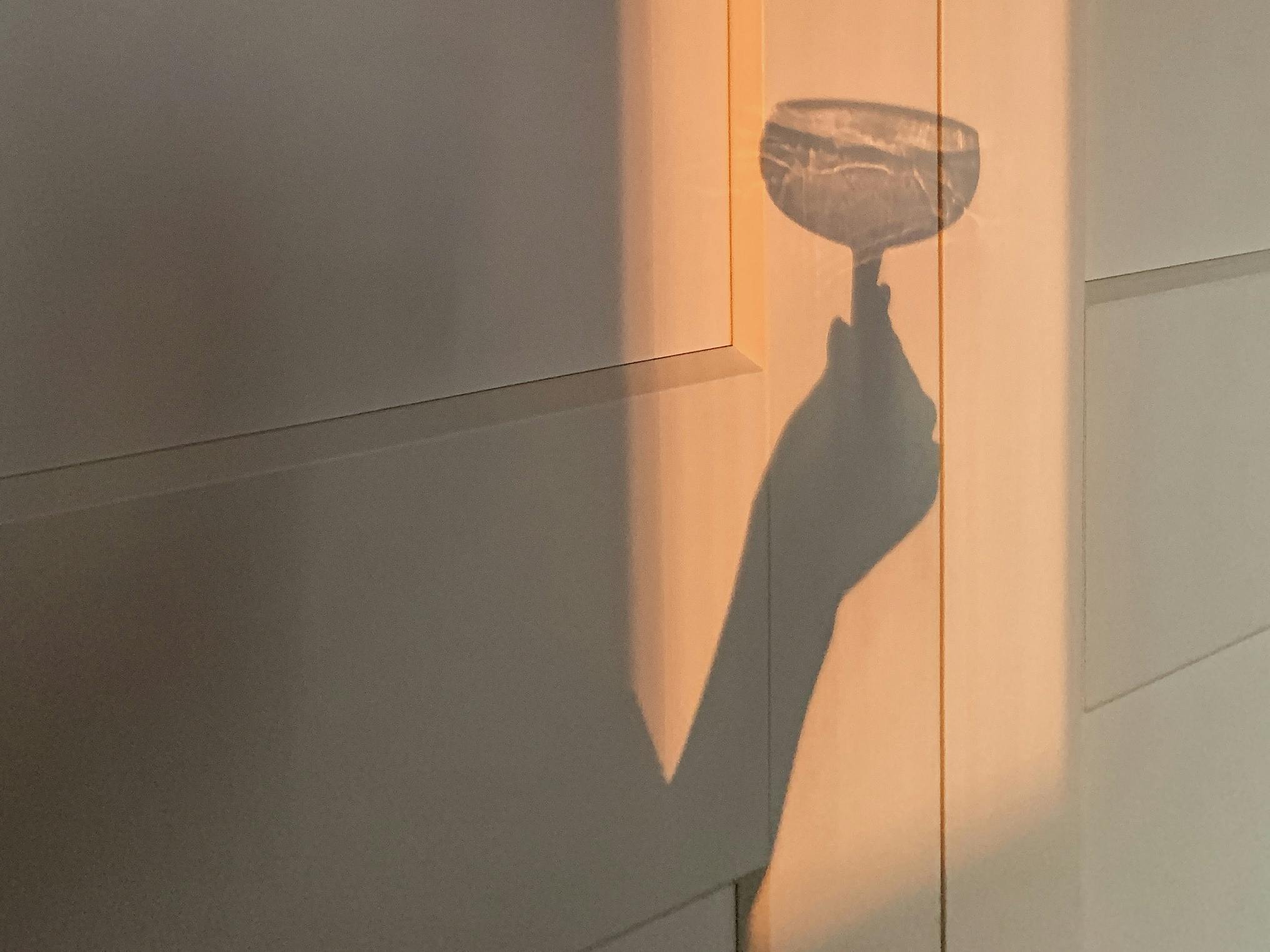 Casted shadow of someone holding a glass.