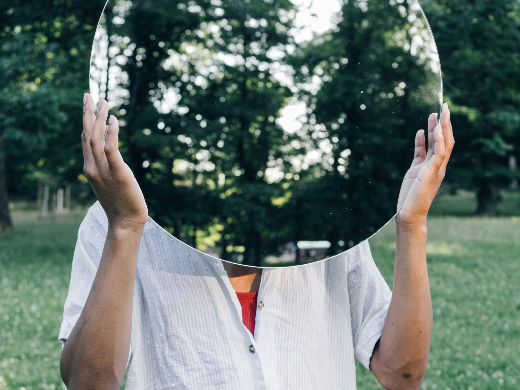 Woman holding mirror over face.